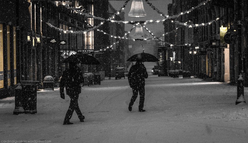 A man with an umbrella is following his own footsteps in the snow / A man with an umbrella has a feeling that someone is following him.